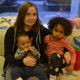 A mom holder her son and daughter on the couch in a family cafe